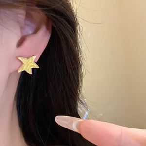 Vista detallada de un pendiente de estrella de esmalte amarillo usado en una oreja