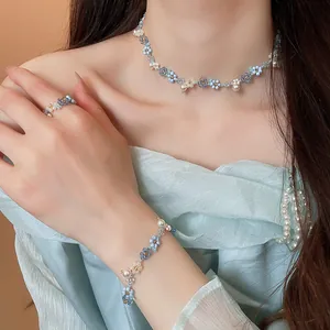 Ensemble de bijoux faits main avec fleurs perlées et perles, porté par un mannequin.