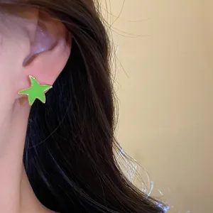 Primer plano de un pendiente de estrella verde lima usado en el lóbulo de la oreja