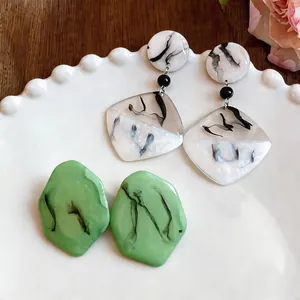 Vue détaillée de boucles d'oreilles en résine marbrée et de clous géométriques verts