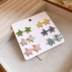 Detalle de seis pares de pendientes de estrella de esmalte de colores en tarjeta