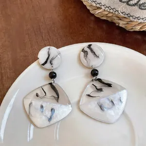 Gros plan de boucles d'oreilles en résine marbrée style encre de Chine