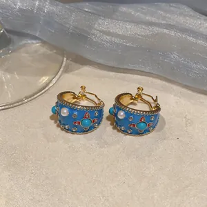 Detailaufnahme von blauen Emaille-Ohrclips mit Perlen- und Türkis-Details im Vintage-Stil