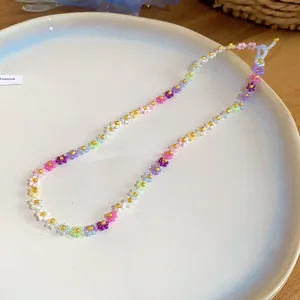 Gros plan d'un collier de perles de fleurs dopamine colorées sur une assiette blanche