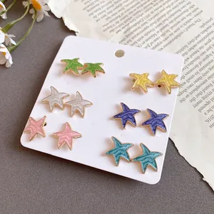 Primer plano de pendientes de estrella en esmalte con aguja de plata en tarjeta.