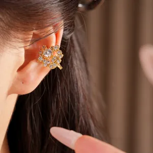 Primo piano di un ear cuff a forma di fiore placcato in oro con zirconi lucenti