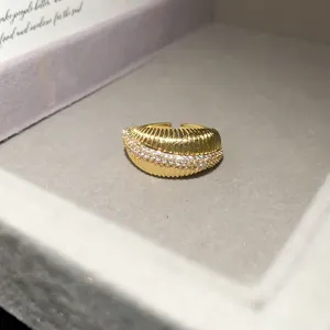 Macro detail of a 14k gold plated textured open ring with sparkling cubic zirconia stones.