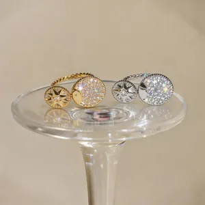 Detailed view of gold and silver eight-pointed star zircon rings on a glass pedestal