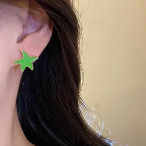 Primer plano de un pendiente de estrella verde en la oreja de una modelo profesional