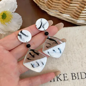 Gros plan sur les boucles d'oreilles en résine marbrée au design géométrique chic