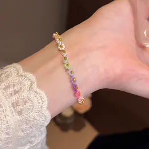 Vue détaillée d'un bracelet de perles à fleurs colorées sur un poignet avec dorures.