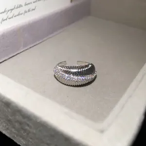 Close-up of silver plated open ring with sparkling zircons and ribbed texture.