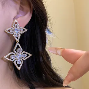 Detailed close-up of gold dangle earrings featuring a sparkling zircon flower pattern