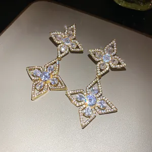 Detailed close-up of elegant gold flower drop earrings featuring sparkling zircon stones.