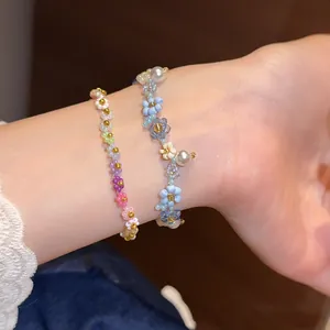Vue détaillée des bracelets de fleurs dopamine colorées et de perles sur un poignet.