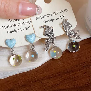 Close-up of silver-tone butterfly and heart earrings with colorful glass ball drops.