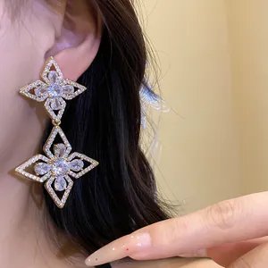 Detailed macro view of elegant silver needle zircon flower drop earrings worn on model ear