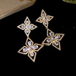 Close-up of elegant gold-toned dangle earrings featuring intricate zircon flower petals