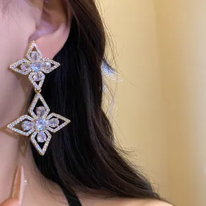 Close-up detail of elegant gold-tone flower drop earrings with sparkling zirconia.