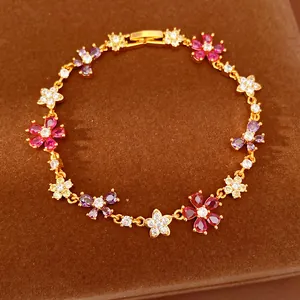 Close-up of gold-plated bracelet with colorful zircon flowers and butterfly charms