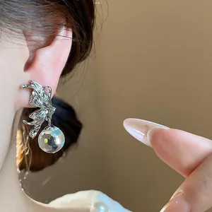 Elegant silver butterfly earrings with a colorful glass ball pendant shown on model ear