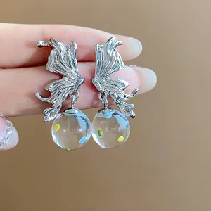 Detailed macro view of silver butterfly earrings with colorful dotted glass balls