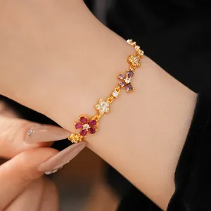 Detailed close-up of a gold-plated bracelet featuring colorful zircon flowers and bows
