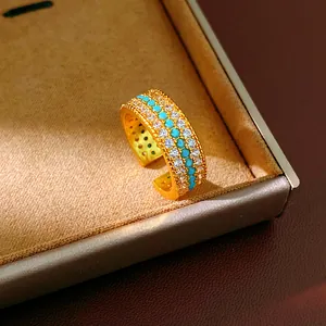 Dettaglio macro di un anello placcato oro a tre file con pietre turchesi e zirconi