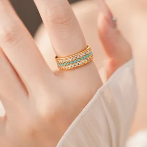 Dettaglio di un anello dorato vintage con tre file di zirconi e perline turchesi