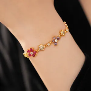 Close-up of gold-plated bracelet featuring multi-colored zircon flowers on wrist.