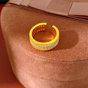 Primo piano dettagliato di un elegante anello d'oro a tre file con zirconi e turchesi
