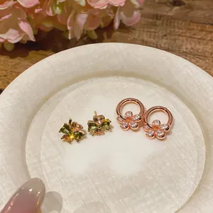 Detailed view of rose gold four-leaf clover and flower stud earrings with zircons