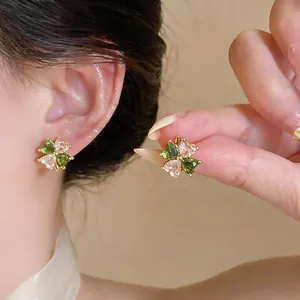 Detailed shot of four-leaf clover earrings with green and clear heart zircons.