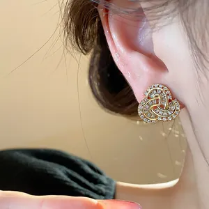 Close-up of gold plated zircon stud earrings with baguette-cut stones on an ear