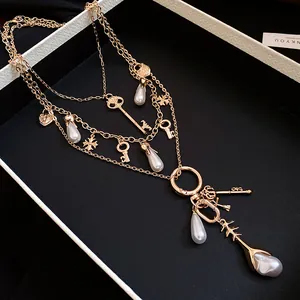 Detailed view of a vintage gold layered necklace with pearl and key charms in a box