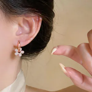 Close-up view of a rose gold flower earring featuring sparkling zirconia on an ear