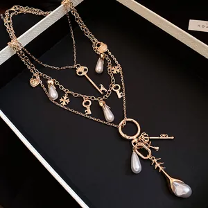 Close-up of multi-layered vintage necklace with gold-toned key and pearl charms