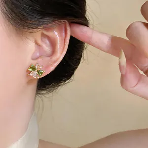 Close-up of green and clear zircon clover stud earring worn on ear