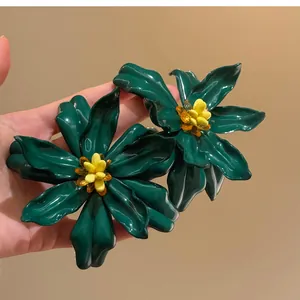 Detailed macro view of dark green acrylic flower earrings with vibrant yellow stamen core.