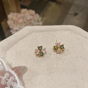 Close-up detail of four-leaf clover stud earrings with pink and green zircon stones.