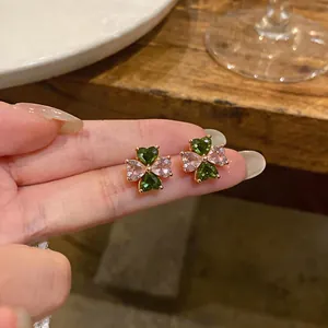 Macro view of elegant four-leaf clover zircon earrings with pink and green heart stones