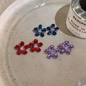 Elegant flower-shaped zircon stud earrings featuring blue, red, and purple crystals.
