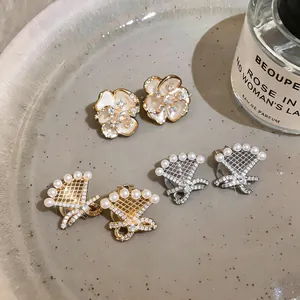 Detailed view of 18k gold plated zircon and pearl ear clips in bow and flower designs