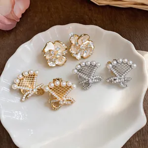 Detailed view of pearl and zircon bow ear clips displayed on a shell tray.