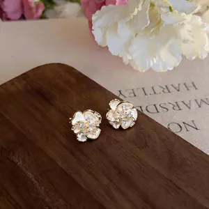 Detail view of flower-shaped zirconia clip-on earrings with white enamel petals