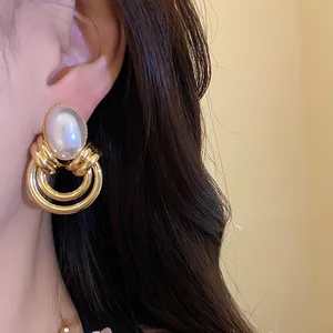 Primo piano di orecchini a cerchio vintage in oro con perla bianca ovale indossati all'orecchio