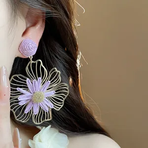 Primo piano di eleganti orecchini a fiore in raffia viola con montatura in metallo cavo