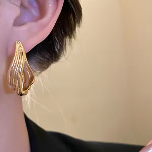 Dettaglio di orecchini d'oro in stile vintage con motivo geometrico testurizzato