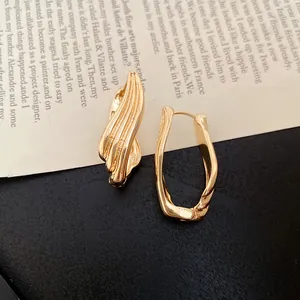 Primo piano di eleganti orecchini a cerchio dorati con trama geometrica su uno sfondo artistico