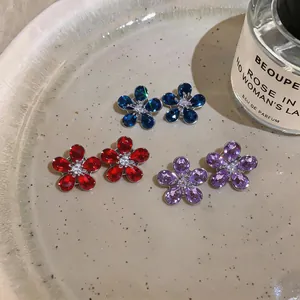 Close-up of sparkling flower-shaped zirconia earrings in red, blue, and purple